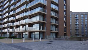 A multi-story residential building with balconies, a paved courtyard, and a sign indicating the building name. - Apartment in Nieuwpoort for 4-people (Nieuwpoort)