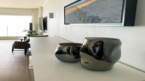 A modern living room with a large painting of a coastal scene, a sofa, and two reflective vases on a white table. - Apartment in Nieuwpoort for 4-people (Nieuwpoort)