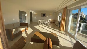 A spacious living room with a sofa, armchairs, and a dining area with chairs and a table. - Apartment in Nieuwpoort near the Sea Wall (Nieuwpoort)