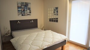 A bedroom with a bed, a headboard, a wall art piece, a window, and a toy on the floor.