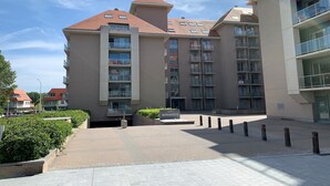 A multi-story building with balconies, a sign reading "BERNARDUS," and a paved courtyard.