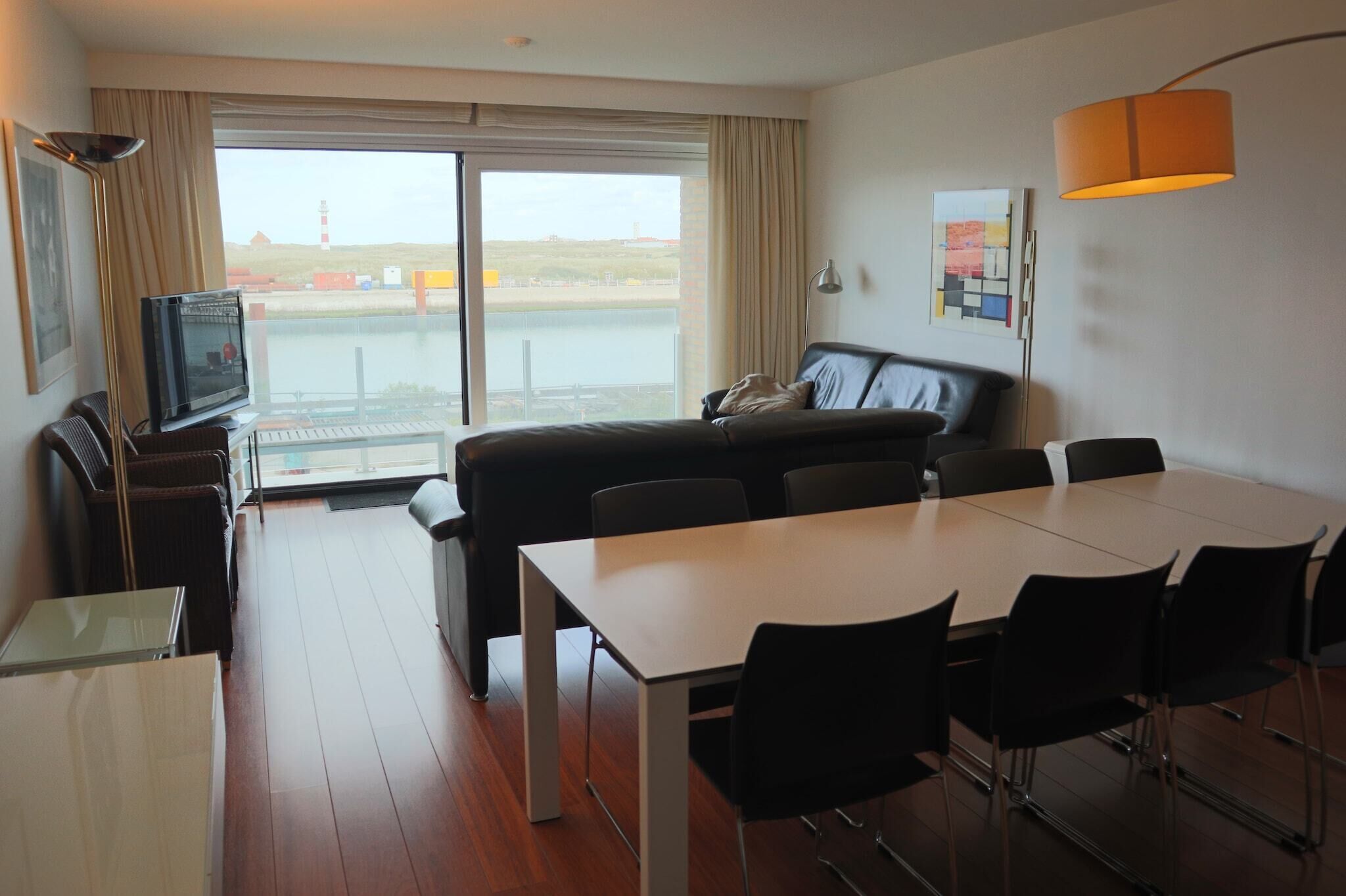 Een moderne hotelkamer met een groot raam, een bank, een eettafel en een televisie.