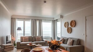 Ein modernes Wohnzimmer mit einer Sofagarnitur, einem Esstisch mit Tellern und einer Vase mit Blumen.