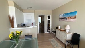 Een moderne keuken met witte kastjes, een glazen eettafel en een vaas met gele bloemen.