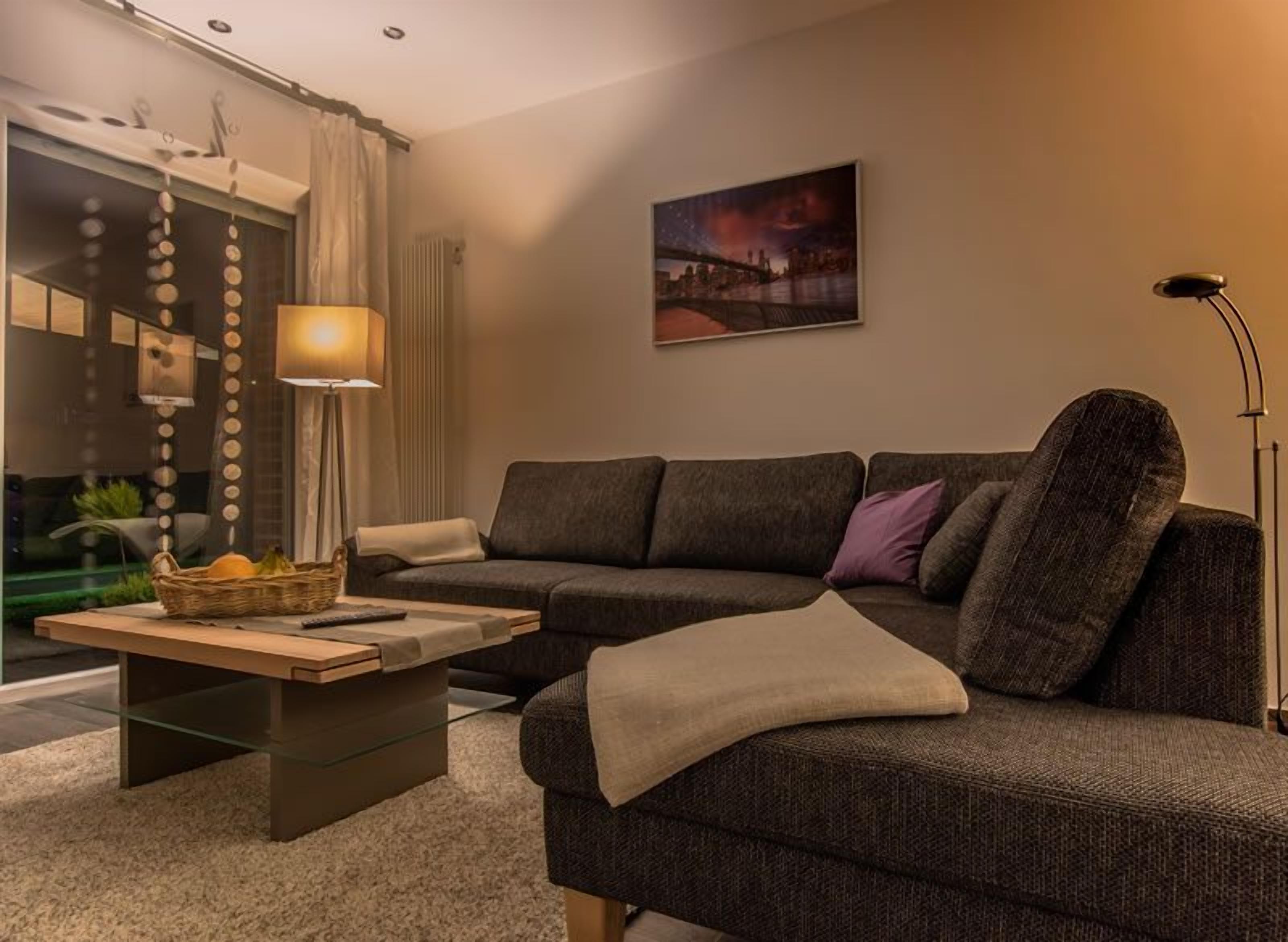 A modern living room with a sectional sofa, a glass coffee table, and a floor lamp.
