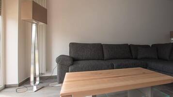 Ein modernes Wohnzimmer mit einem grauen Ecksofa, einem Holztisch und einer Stehlampe.