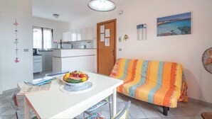 Un espace de vie compact comprenant un coin repas, une kitchenette et un canapé agrémenté d’une couverture colorée.