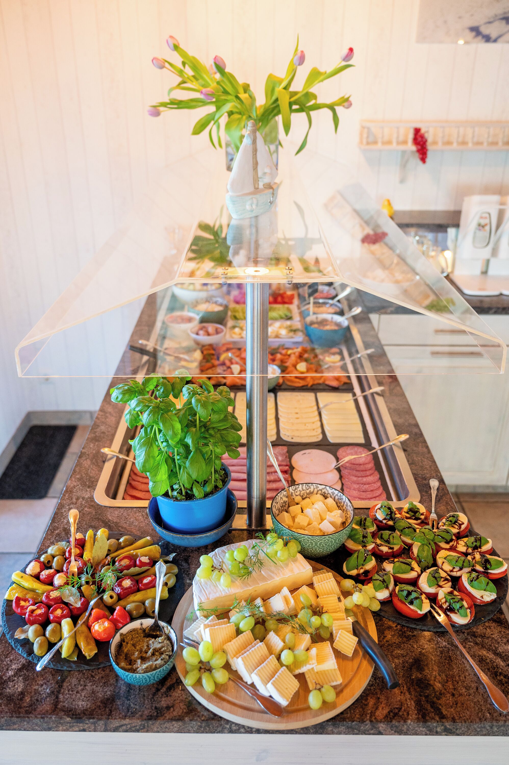 A buffet table with various food items, including cheese, fruits, and dips, arranged on a marble countertop.