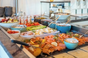 A buffet with various food items including fruits, vegetables, and smoked salmon. - Hotel Villa Sonneck - Adults Only (St. Peter-Ording)