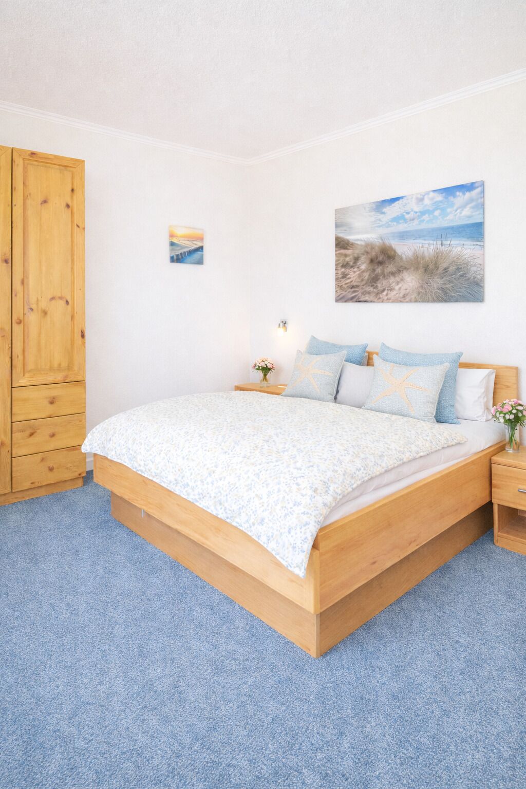 Un dormitorio con cama de madera, mesita de noche, armario de madera y decoración de pared con temática playera.