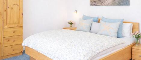 Un dormitorio con cama de madera, mesita de noche, armario de madera y decoración de pared con temática playera.