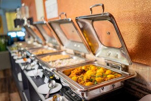 A buffet line with various food items in metal serving trays. - ZAN LODGE (Malé)