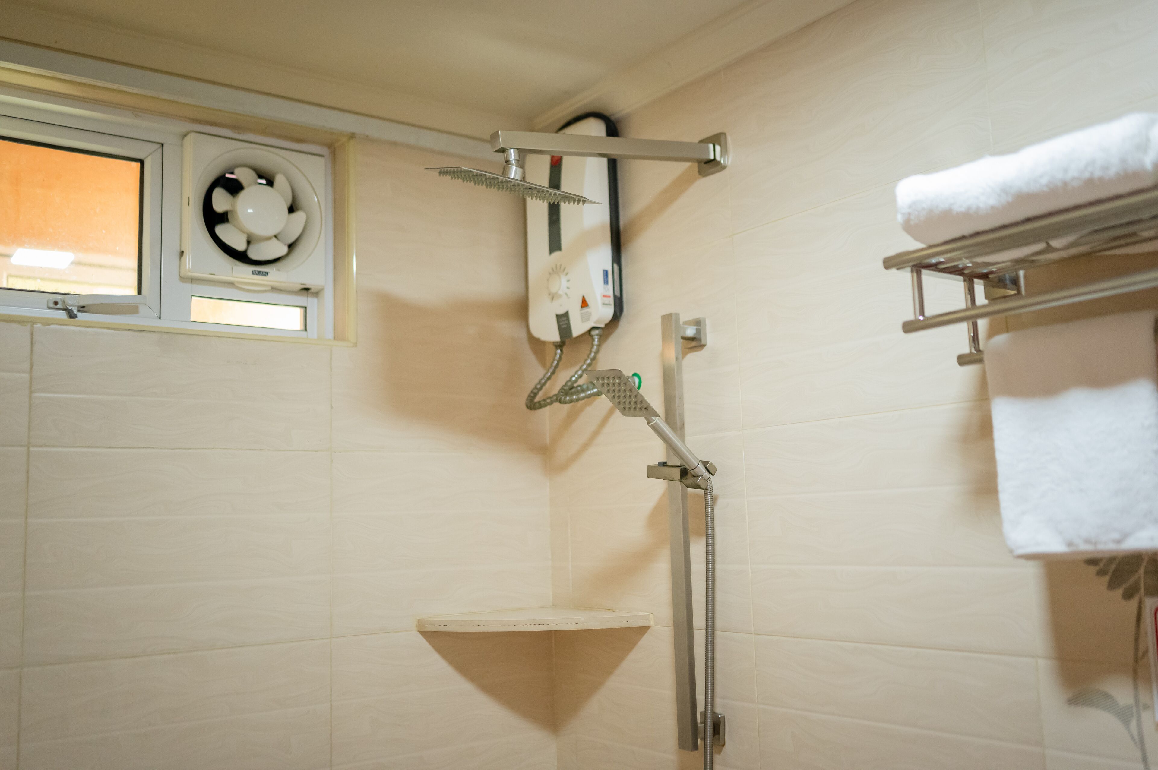 A shower with a handheld showerhead, a towel rack, and a ventilation fan.