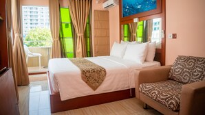 A hotel room with a bed, a sofa, a painting, and a view of a building through the window. - ZAN LODGE (Malé)