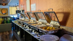 A buffet line with multiple food stations, each with a metal serving tray and a lid. - ZAN LODGE (Malé)
