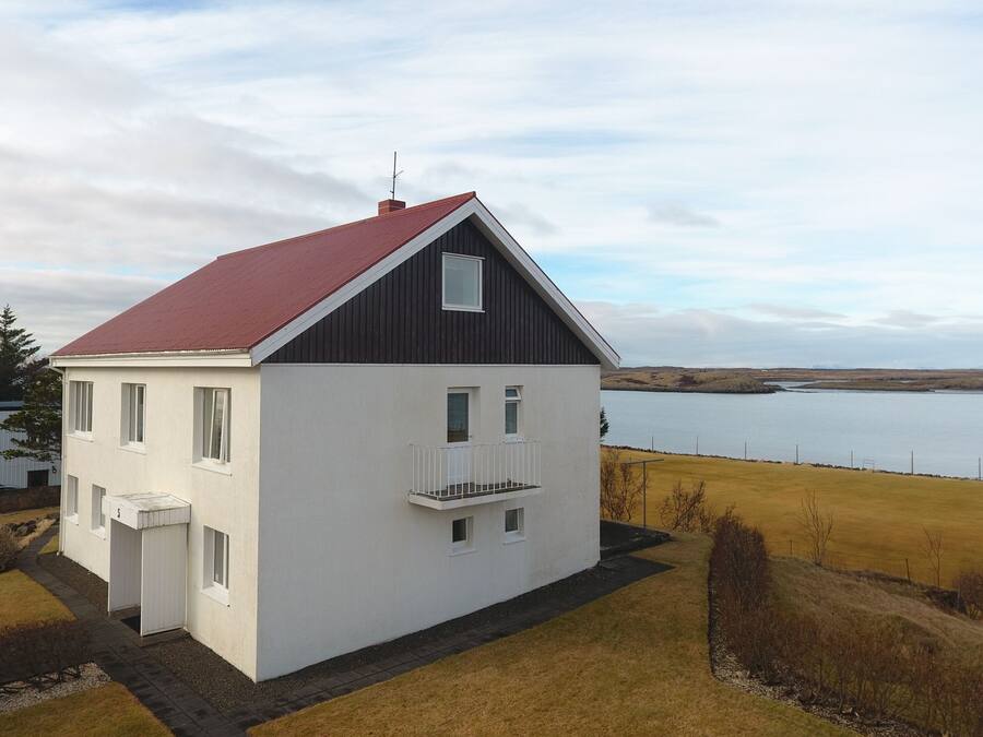 A two-story house with a red roof, white exterior walls, and a balcony.