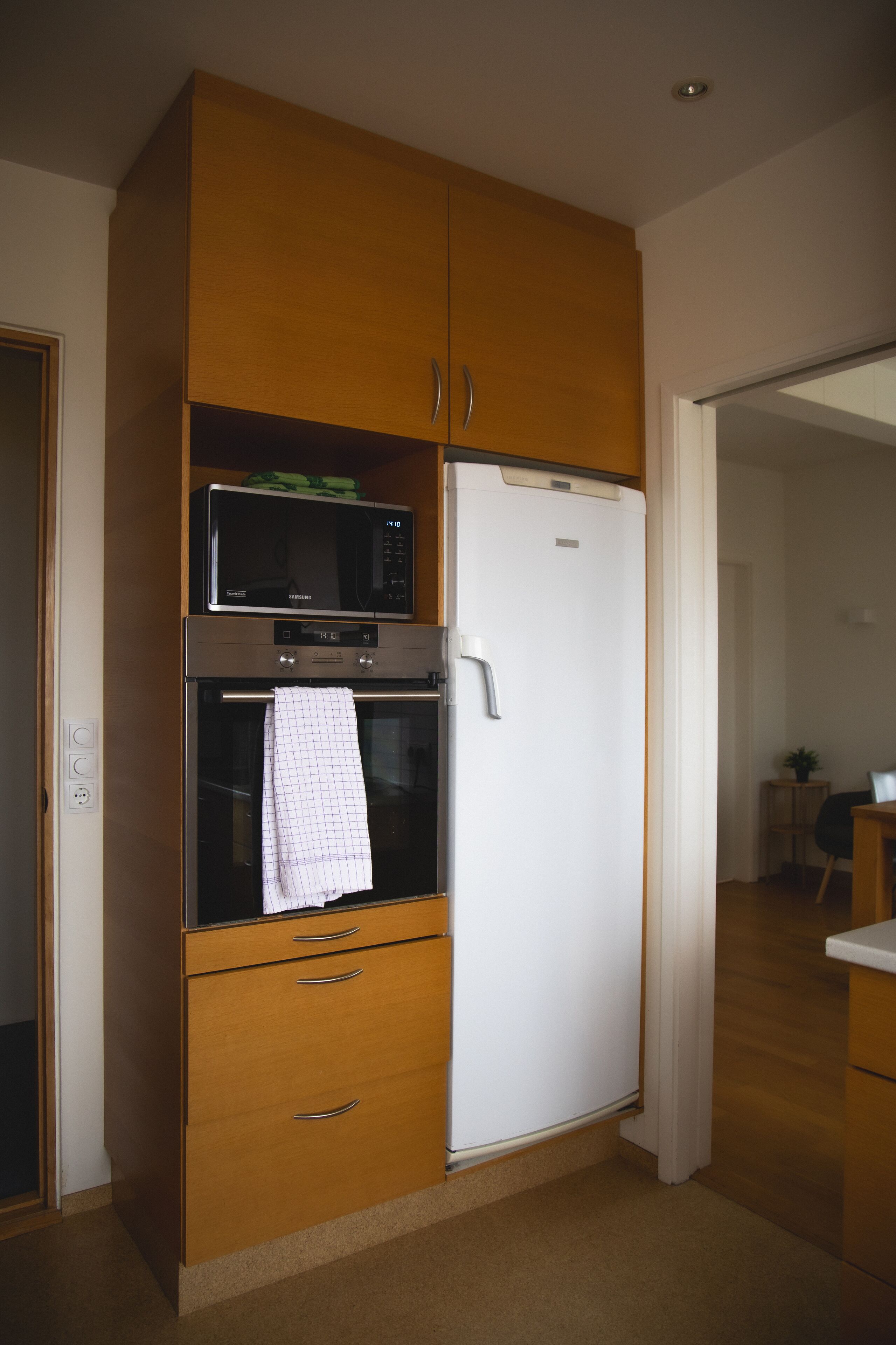 A kitchen with a microwave, oven, and white refrigerator.