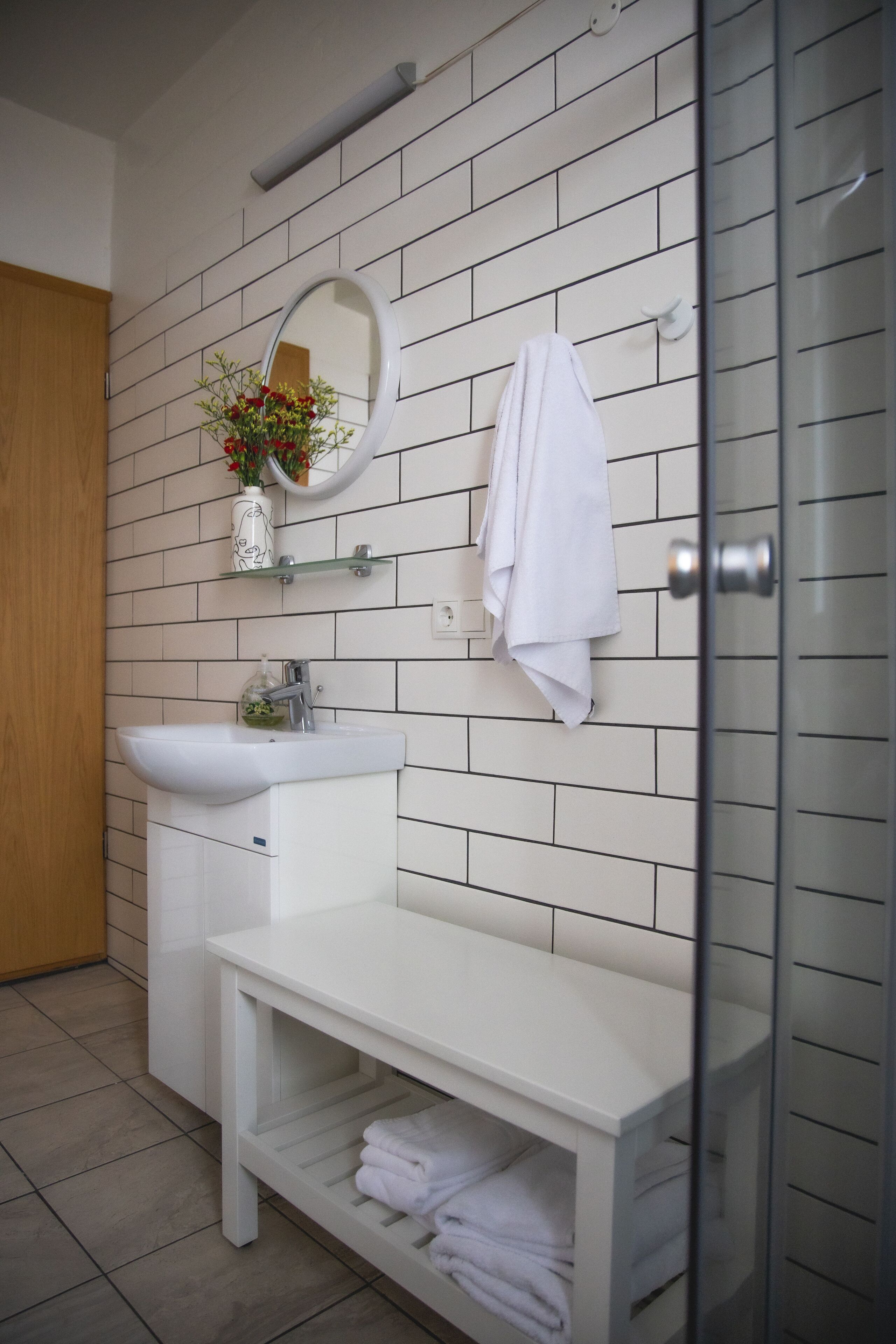 A modern bathroom with a white sink, mirror, and towel rack.