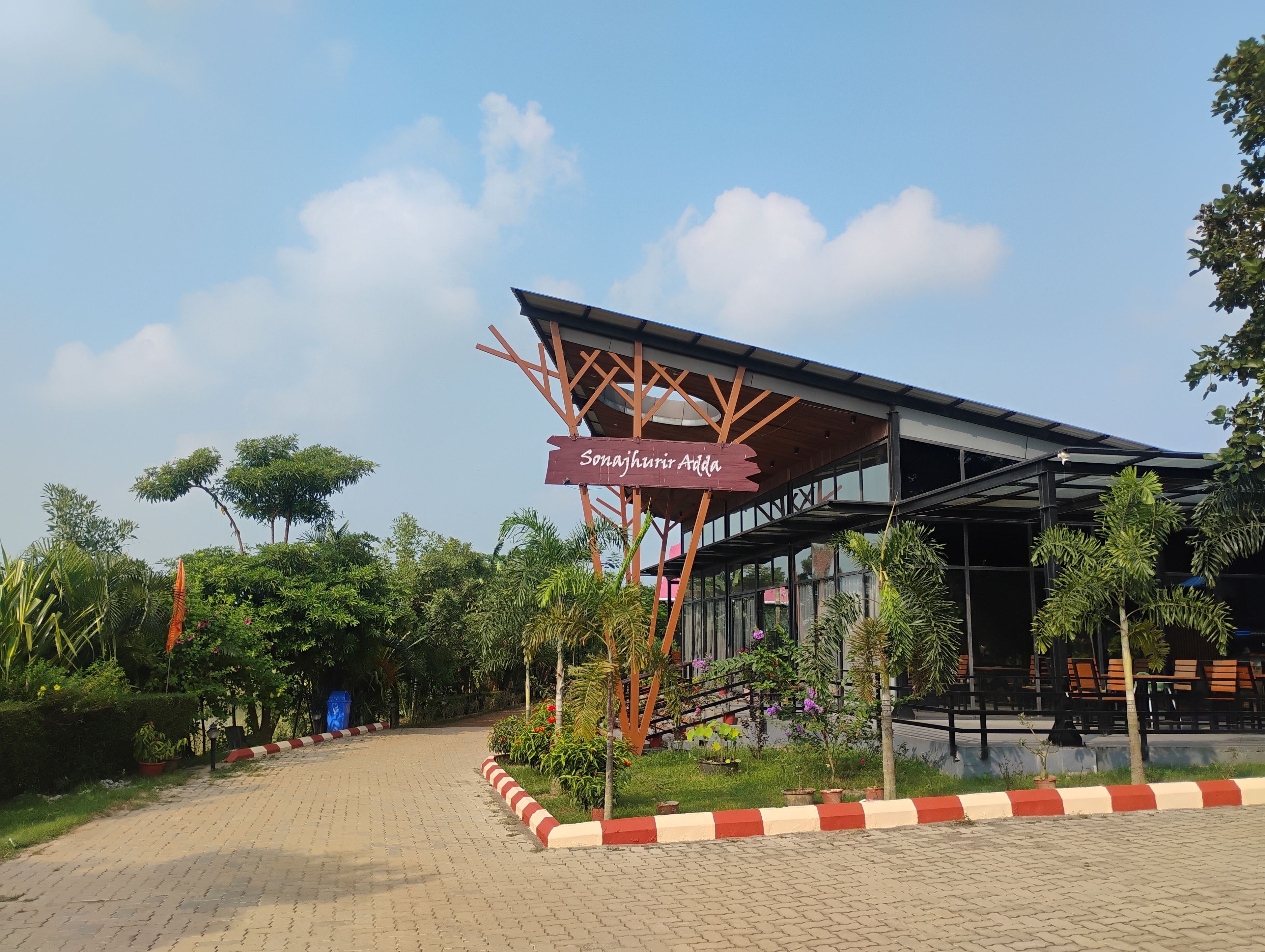 A building with a sign reading 'Sonajhuri Adda' and a covered outdoor area with seating.