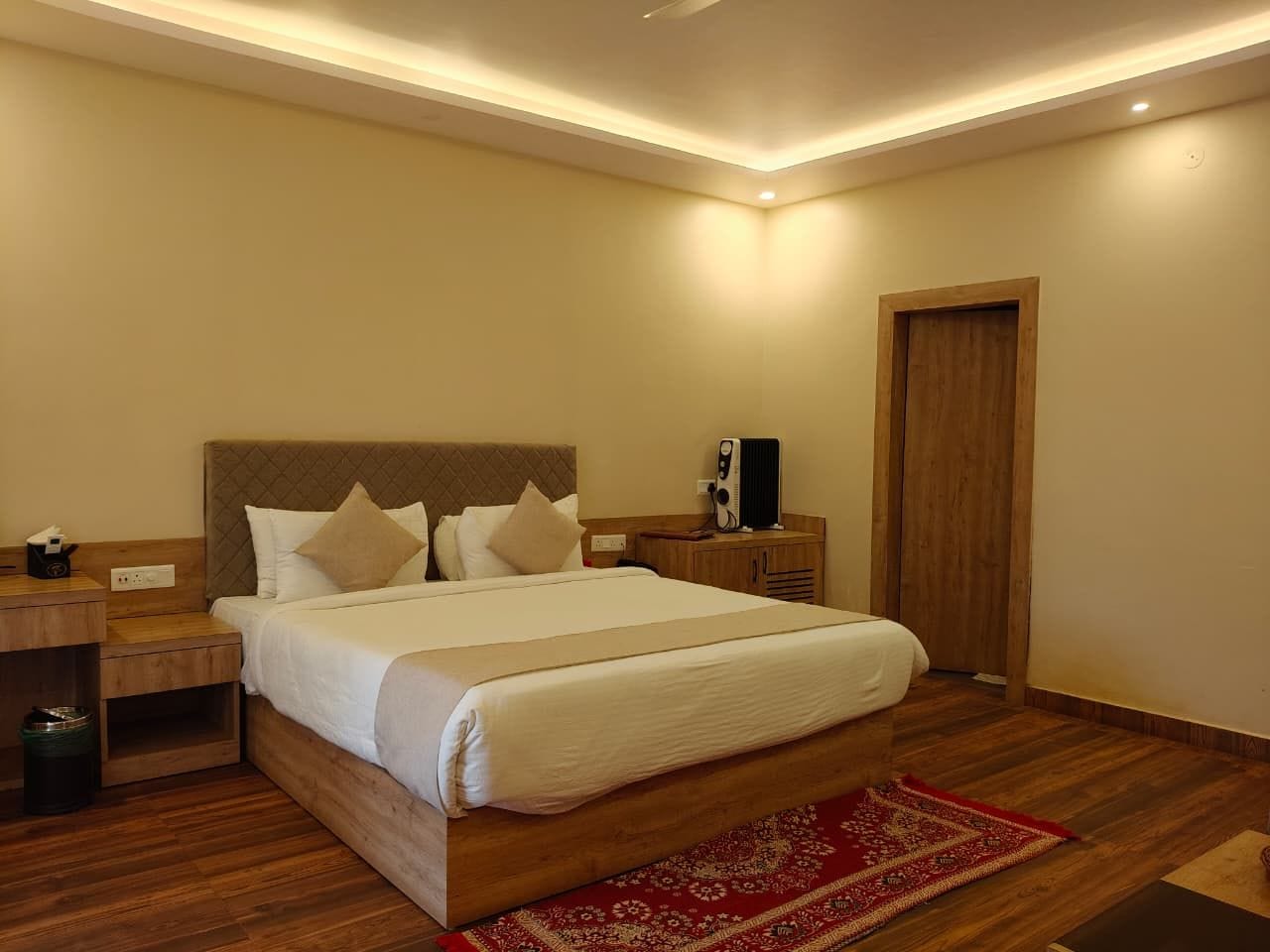 Habitación de hotel con cama, mesita de noche y un altavoz.