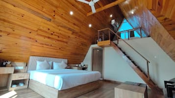 Un intérieur en bois avec un lit, un escalier et un ventilateur de plafond.