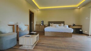 A modern hotel room with a large bed, a sofa, a coffee table, and a desk. - Hotel Sonajhurir Adda - Shantiniketan  (Bolpur)