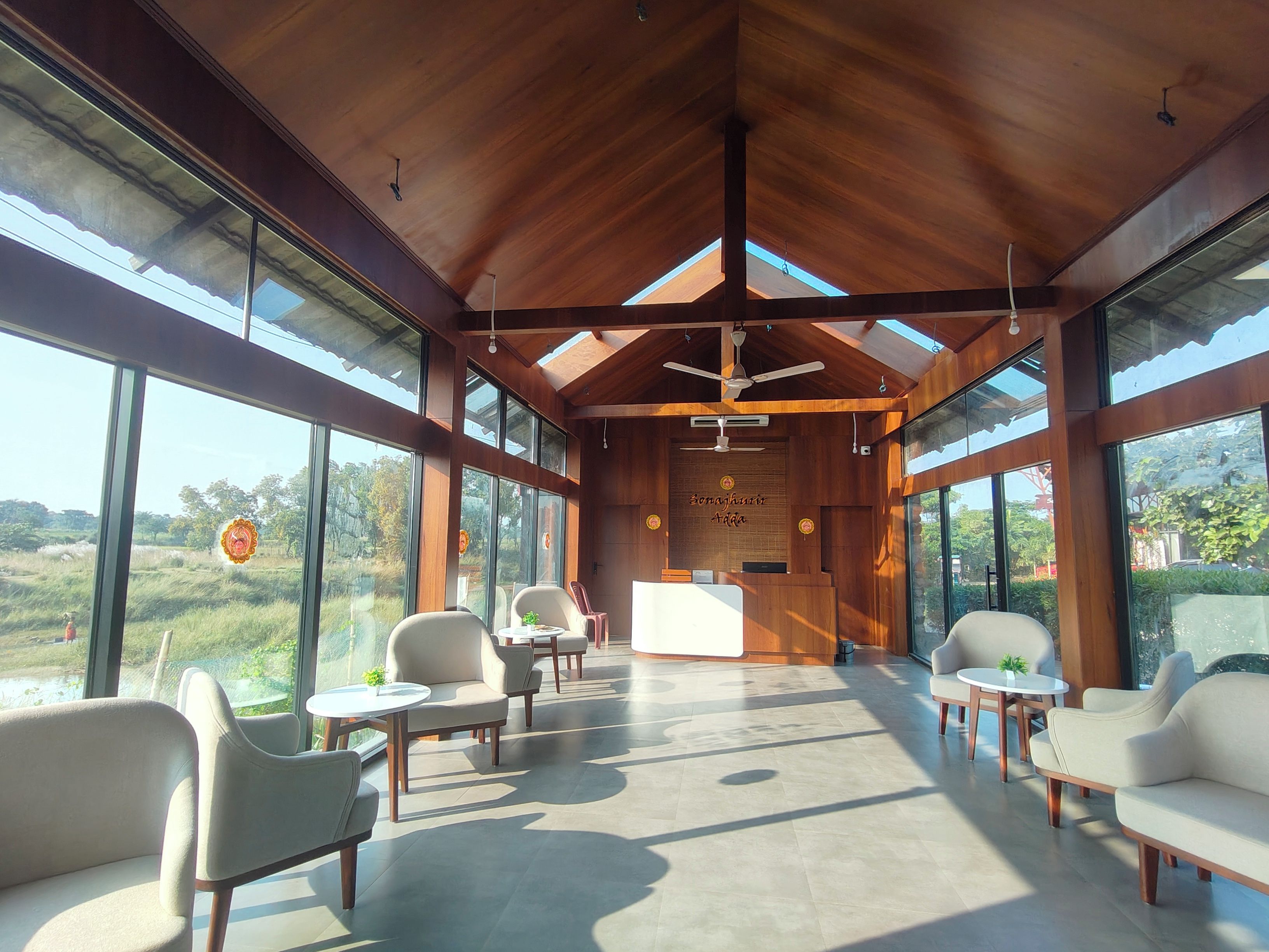 A spacious, modern interior with large windows, wooden ceiling beams, and a reception desk.