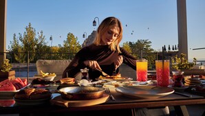 A dining table with various dishes, a drink, and a person eating. - Breeze Of Cappadocia (Nevsehir)