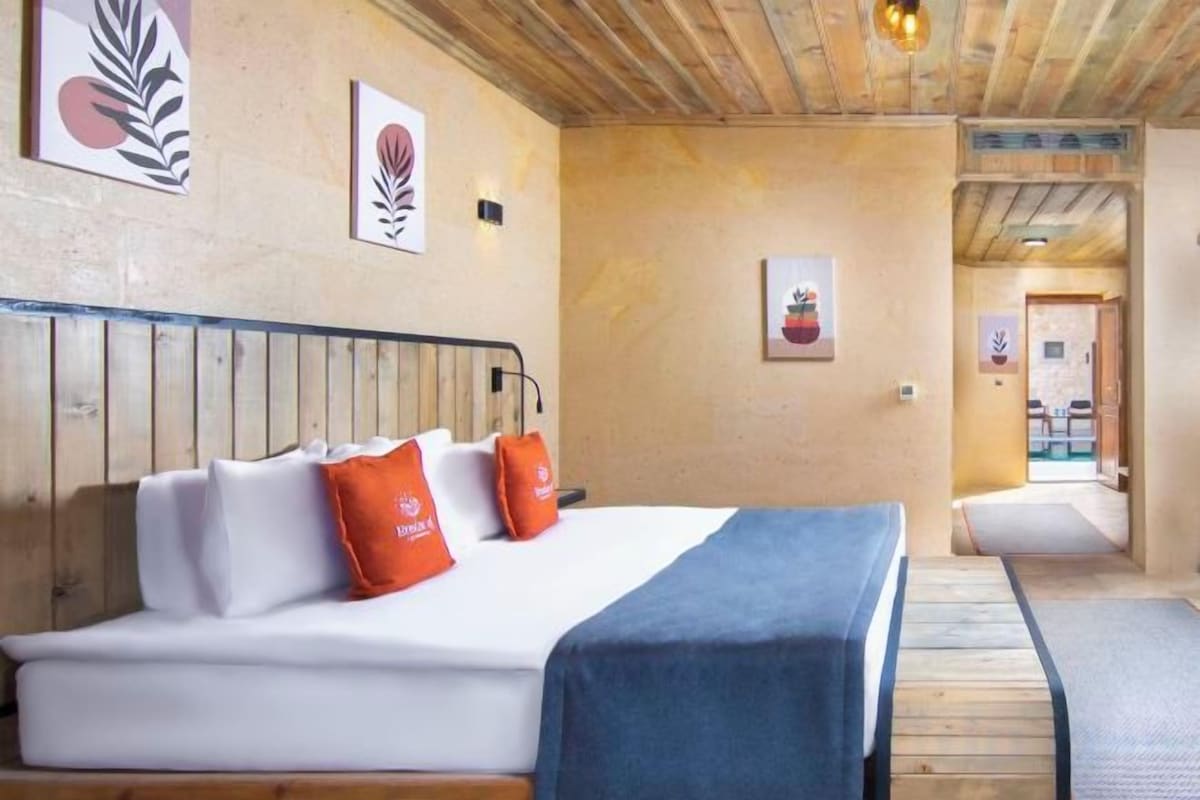 A hotel room with a bed, wooden headboard, and a view of the hallway.