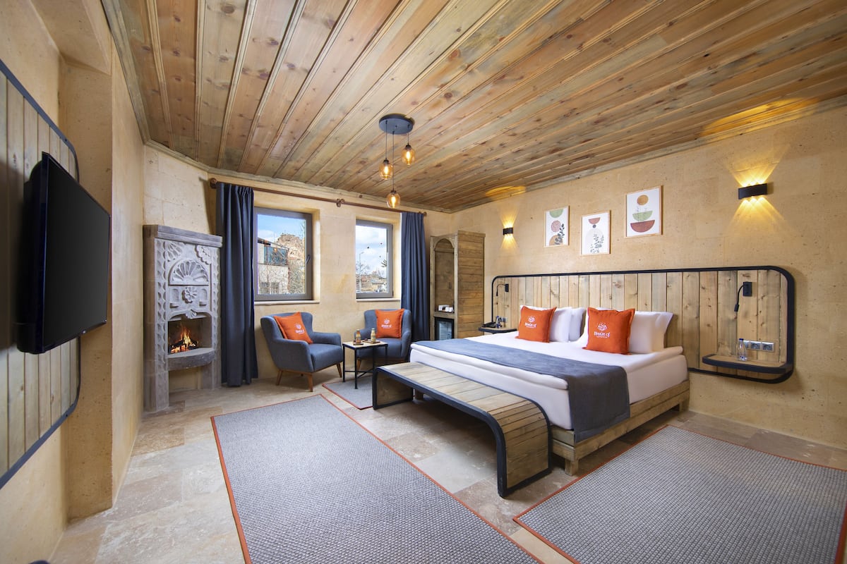 A cozy room with a bed, a desk, and a fireplace.