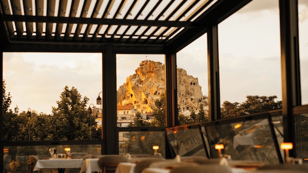 A restaurant with tables and chairs arranged under a wooden pergola with large windows. - Breeze Of Cappadocia (Nevsehir)
