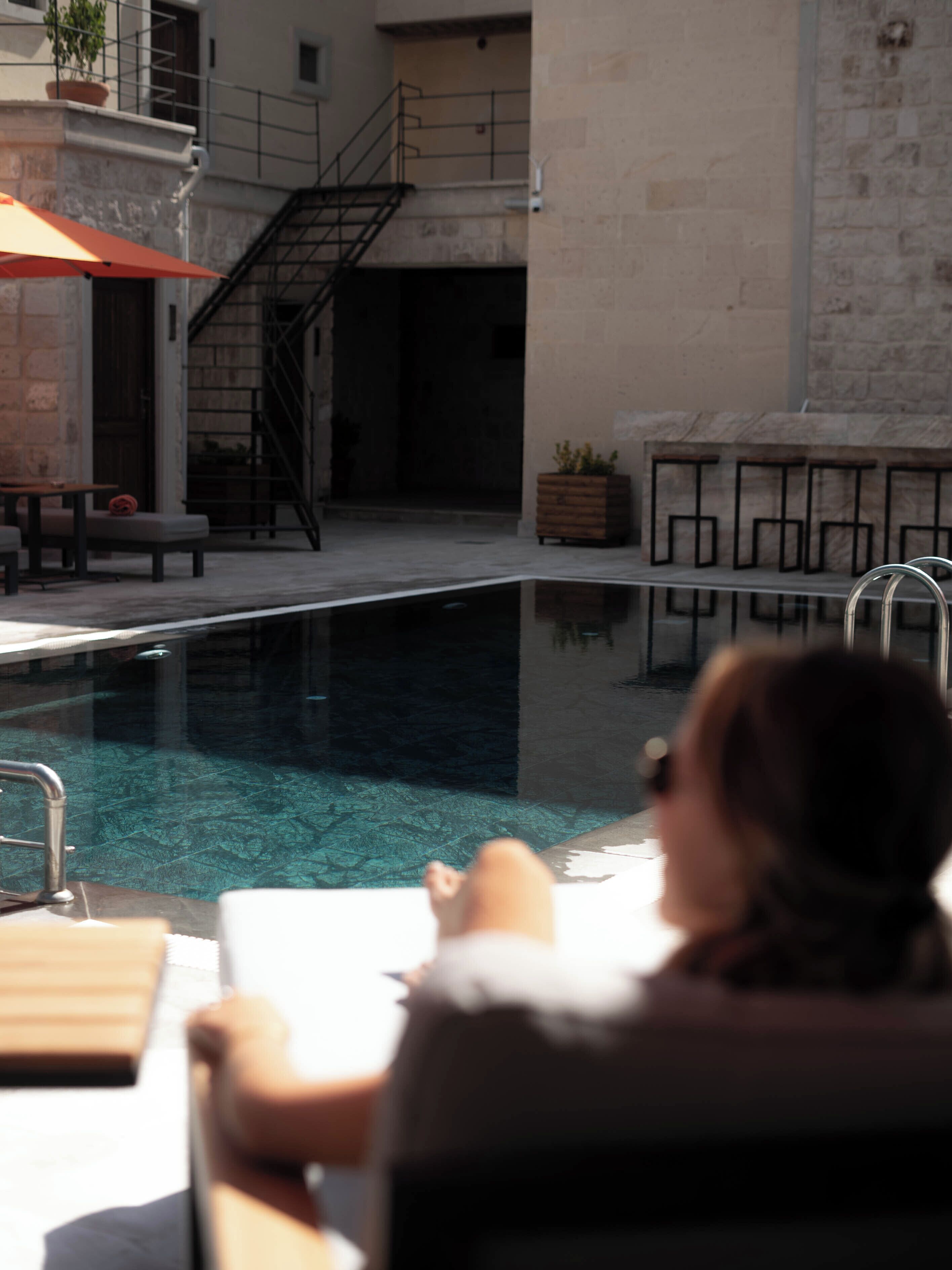 A poolside area with a lounge chair, a small table, and a potted plant.
