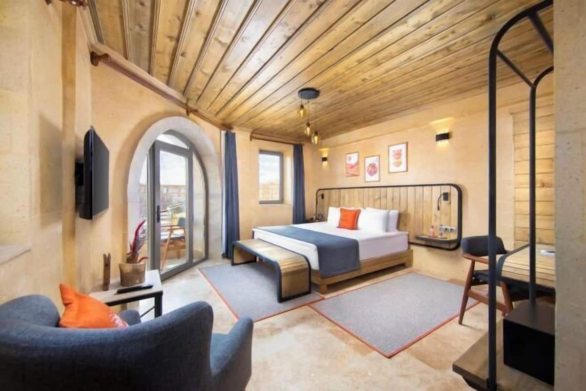 A room with a bed, a chair, a TV, and a window.