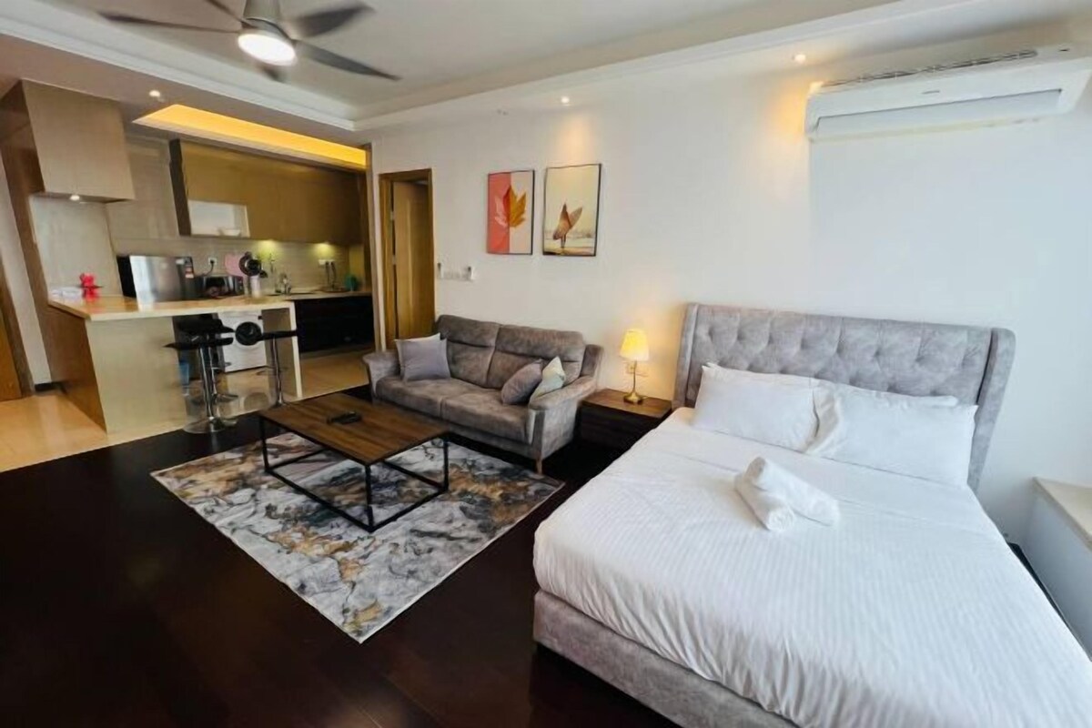 Une chambre d’hôtel moderne équipée d’un grand lit, d’un canapé, d’une table basse et d’une kitchenette.