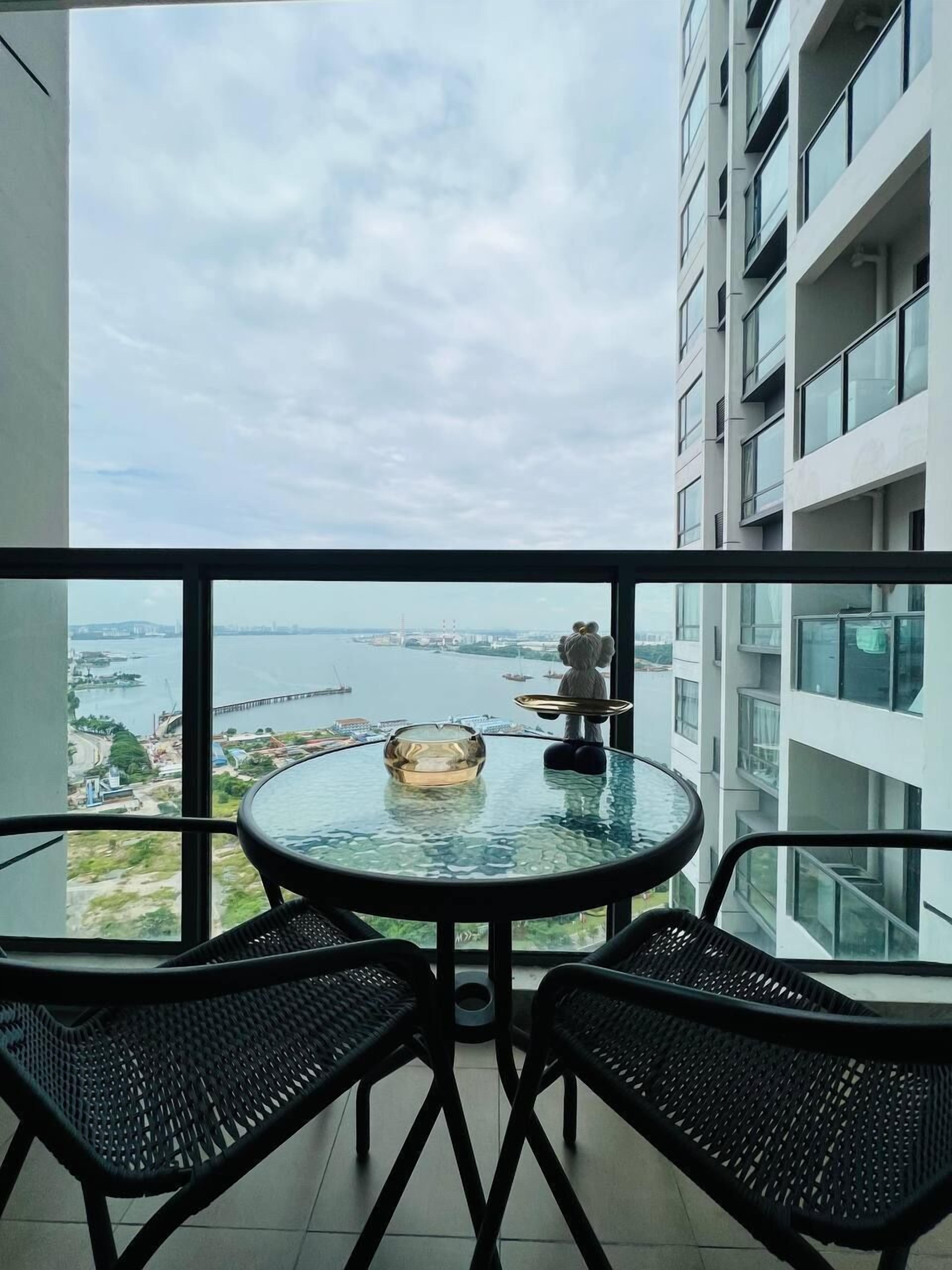 Un balcone con un tavolo e sedie in vetro, con vista su un tratto d'acqua e un ponte.