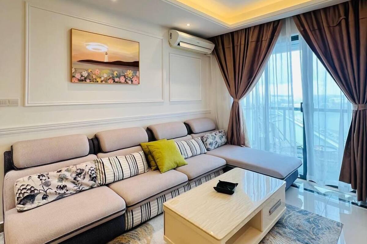 Un saló modern amb un sofà modular, una taula de centre i una finestra gran amb cortines.