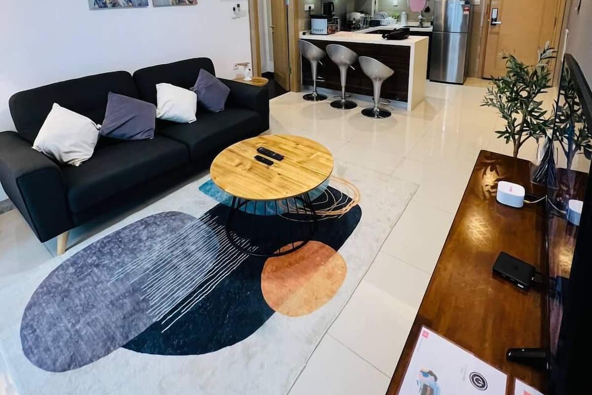 Un saló modern amb un sofà negre, una taula de centre de fusta i una zona de menjador amb taula i cadires de fusta.