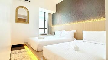 A hotel room with two beds, a large mirror, and a window with curtains.