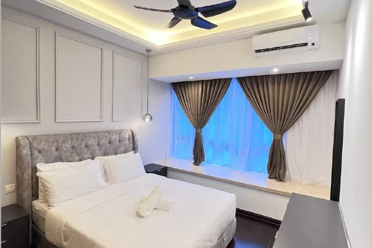 Habitació d'hotel moderna amb un llit gran, un ventilador de sostre, un aparell d'aire condicionat i una finestra amb cortines.