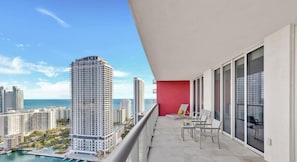 A balcony with a view of high-rise buildings and a body of water.
