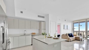 Une cuisine moderne dotée d’un îlot central, d’un coin repas avec un canapé et d’une grande fenêtre offrant une vue sur la ville.