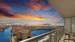 A balcony with a view of a cityscape, a river, and a marina with boats.