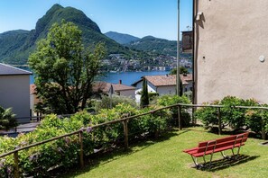Un banc rouge, placé dans un espace verdoyant, d’où l’on peut admirer un lac et des montagnes.