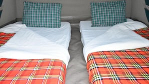 A twin room with two beds, each with a plaid bedspread and matching pillows.