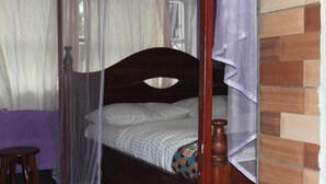 Une chambre à coucher avec un lit en bois, un petit tabouret et une couverture violette.