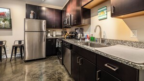 A modern kitchen with dark wood cabinets, stainless steel appliances, and a granite countertop. - The West End Flats (Roanoke)