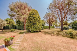 A well-maintained garden with various trees and a paved pathway. - Large lakeside villa (Lesa)