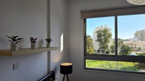 Una habitación con ventana, estante con adornos y una lámpara.