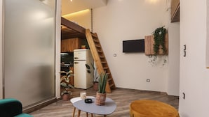 Un espace de vie moderne comprenant un escalier en bois, un coin cuisine et un espace détente avec une table et des chaises.