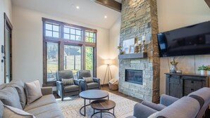 A spacious living room with a stone fireplace, comfortable seating, and a flat-screen TV mounted above the fireplace. - Family Retreat w/ Suncadia Pool Access (Cle Elum)